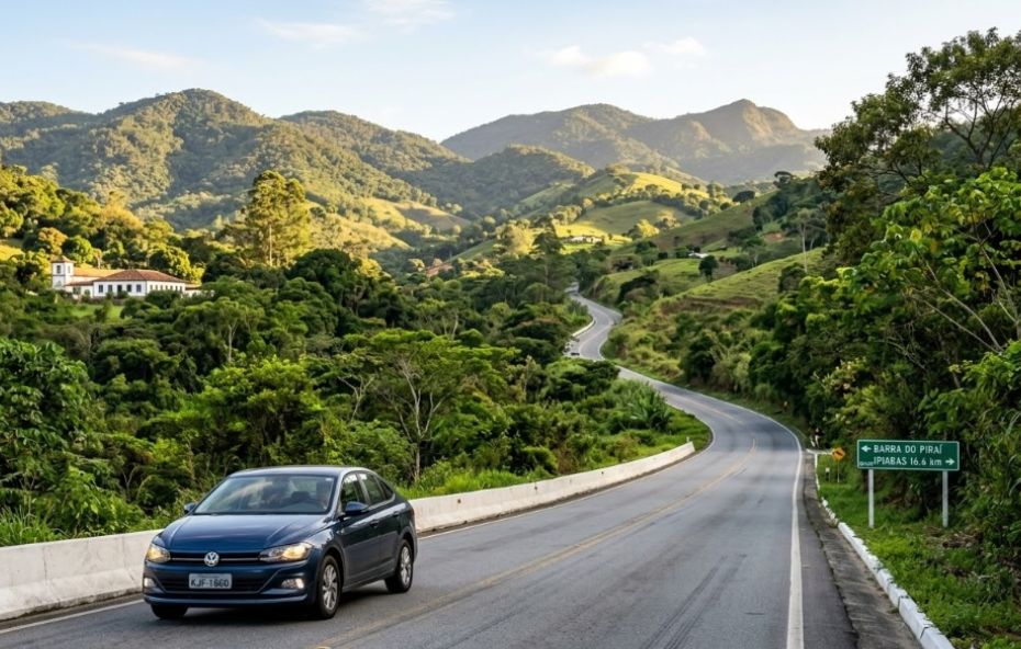 Um carro Volkswagen sedan azul dirige por uma estrada sinuosa cercada por densas colinas verdes no interior do Rio de Janeiro, passando por uma placa de trânsito verde apontando para Barra do Piraí e Ipiabas.