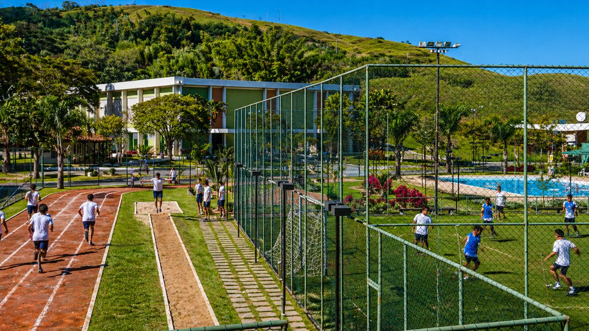 Vista panorâmica das instalações esportivas do Centro Cultural Aracy Carvalho Di Biase em Barra do Piraí mostrando alunos na pista de atletismo e quadras externas.