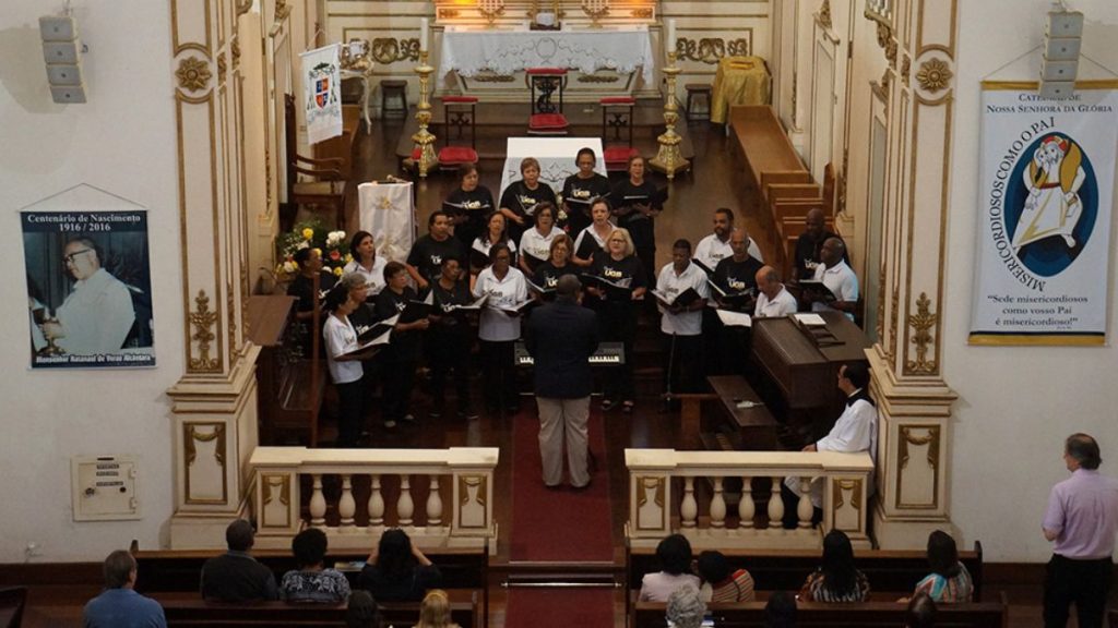 Fotografia em ângulo elevado do Coral UGB se apresentando na nave da Catedral Nossa Senhora da Glória em Barra do Piraí.