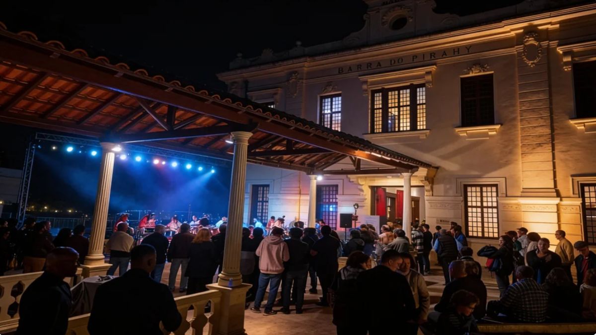 Fotografia noturna de um show musical em palco iluminado com público reunido na plataforma da estação ferroviária de Barra do Piraí.
