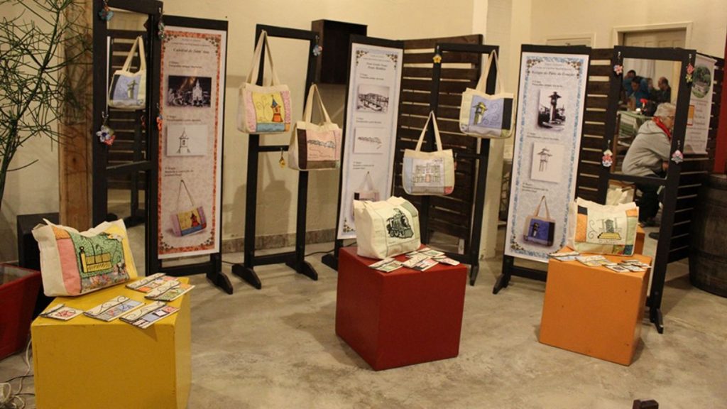 Exposição de bolsas artesanais bordadas com temas históricos e painéis informativos no Centro Cultural Aracy Carvalho Di Biase em Barra do Piraí.