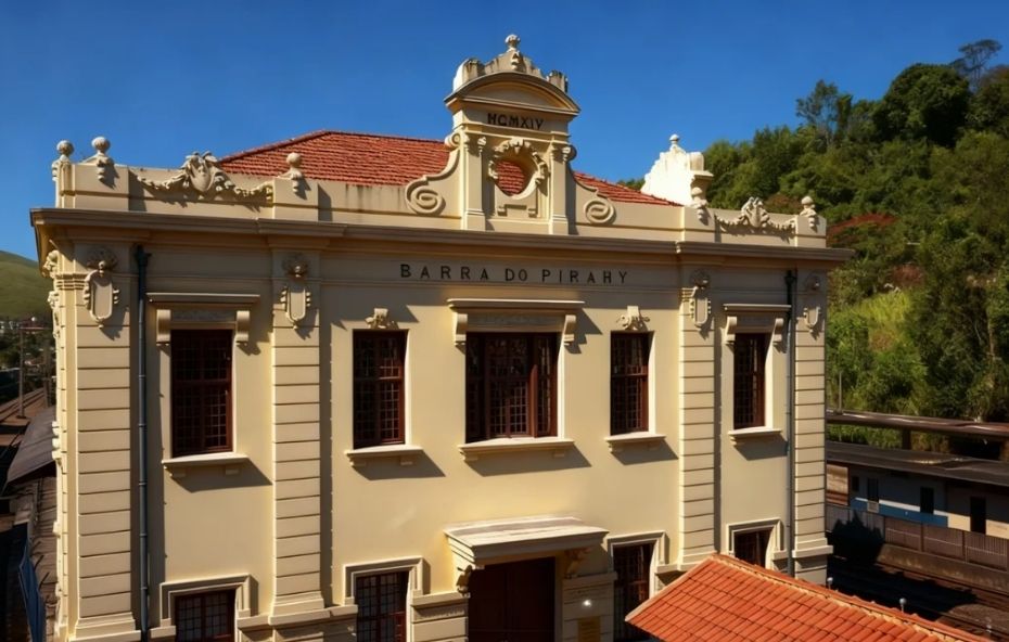 Fotografia da fachada frontal do Centro Cultural Rosemar Muniz Pimentel destacando a arquitetura imperial amarela com a inscrição Barra do Pirahy e detalhes neoclássicos sob um céu azul.