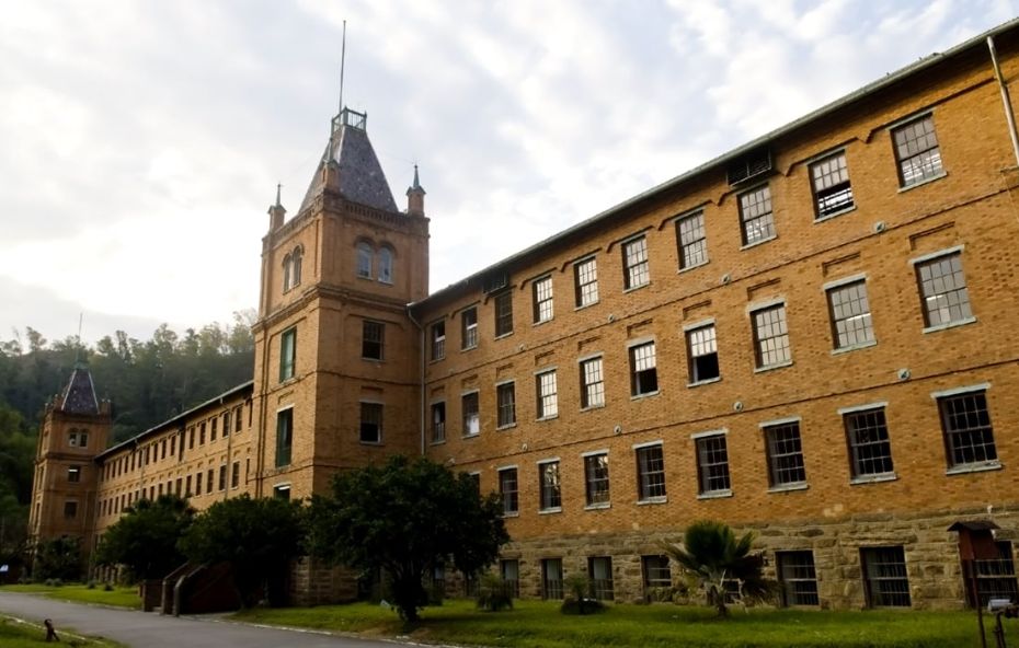 Edifício industrial antigo e extenso construído em tijolos vermelhos com várias janelas enfileiradas e torres laterais em Paracambi sob céu claro.