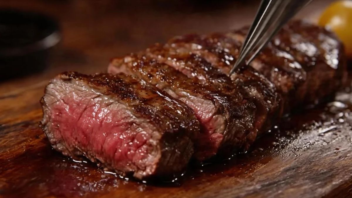 Picanha fatiada em tiras grossas sobre uma tábua de madeira com o centro rosado e suculento em destaque visual.