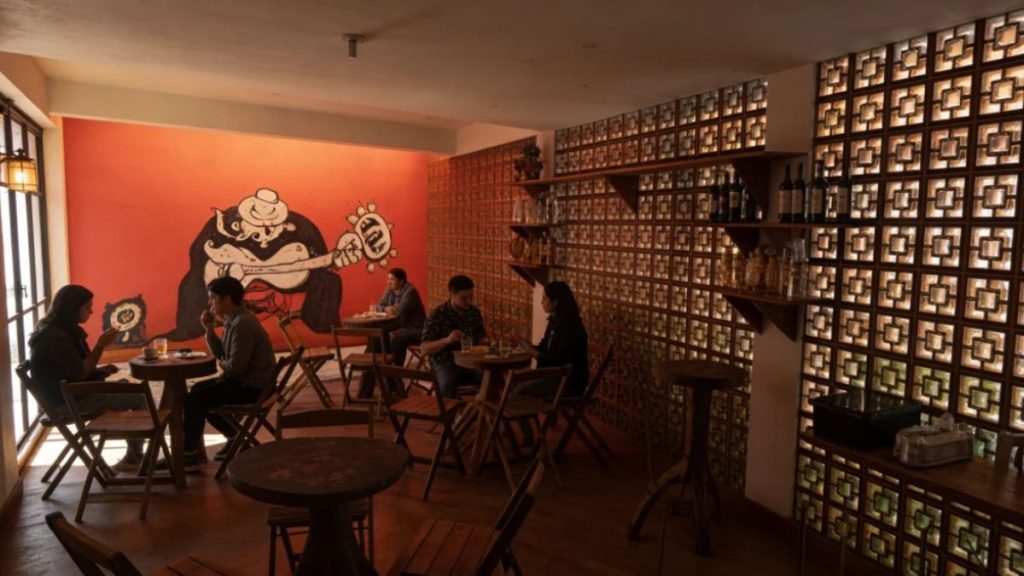 Área interna da Pousada Blues com mesas ocupadas por hóspedes, decoração acolhedora e iluminação quente em ambiente gastronômico intimista.