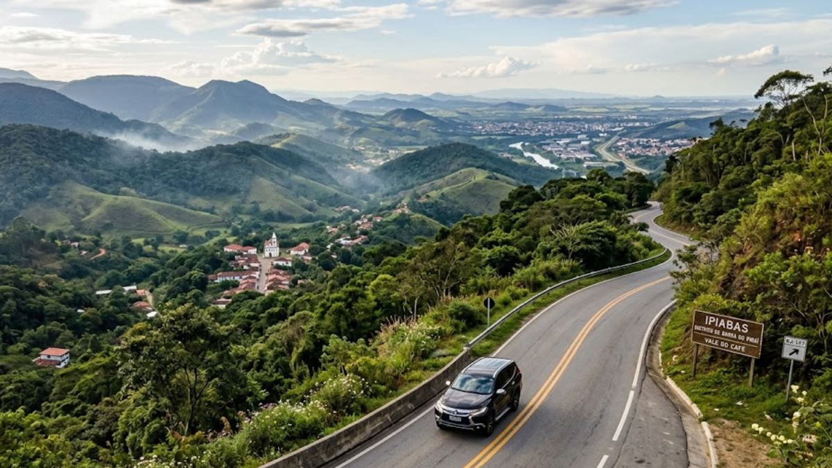 Fotografia aérea de uma estrada sinuosa na montanha com um carro preto, avistando o distrito de Ipiabas ao fundo.
