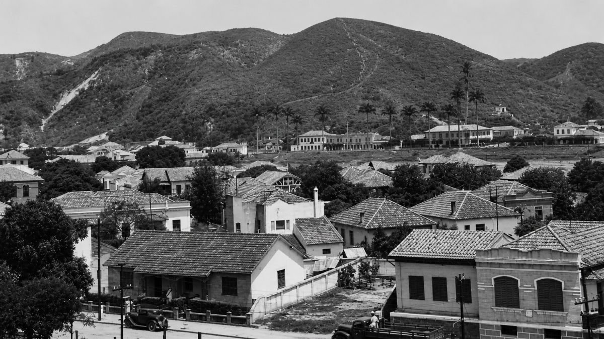 Fotografia em preto e branco mostrando casas antigas com telhados cerâmicos e morros.
