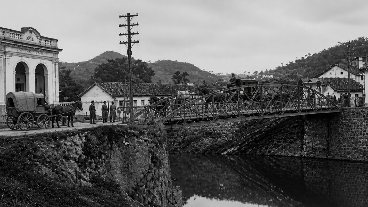 Fotografia antiga em preto e branco mostrando uma carruagem atravessando uma ponte metálica em arco sobre o Rio Piraí.