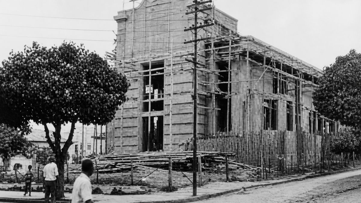 Fotografia antiga em preto e branco mostrando a estrutura de alvenaria da igreja em obras cercada por andaimes de madeira.