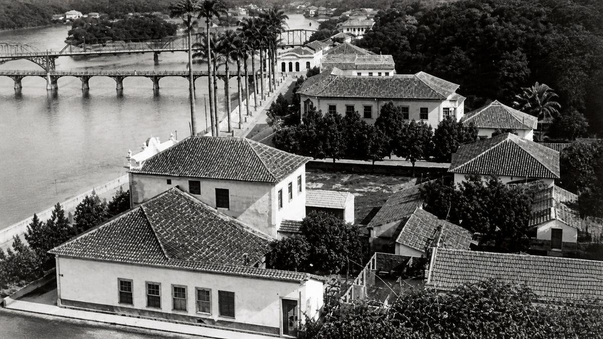 Fotografia aérea em preto e branco de casarões antigos próximos ao rio e pontes.