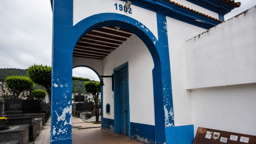 Fotografia em ângulo lateral de um pórtico branco e azul com a data de 1902 inscrita acima de um arco.