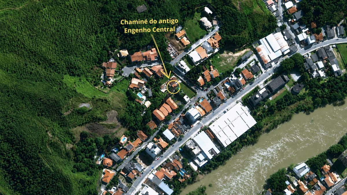 Vista aérea de satélite mostrando o bairro residencial densamente ocupado ao lado do rio com indicação para a chaminé.
