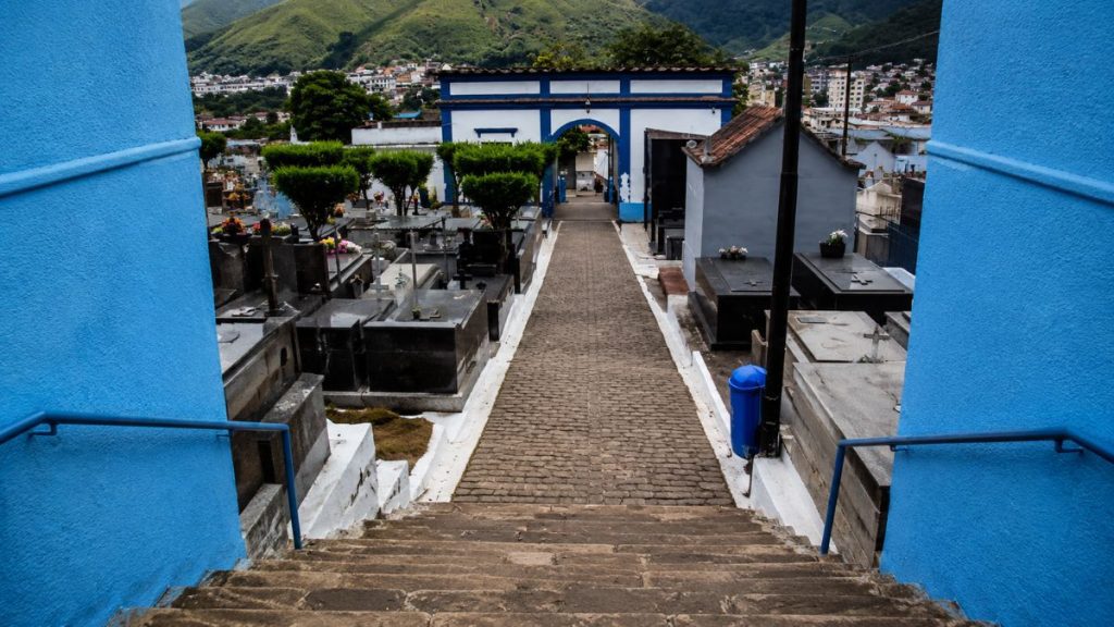 Fotografia do topo de uma escadaria de pedra olhando para baixo em direção a um caminho de paralelepípedos e pórtico.